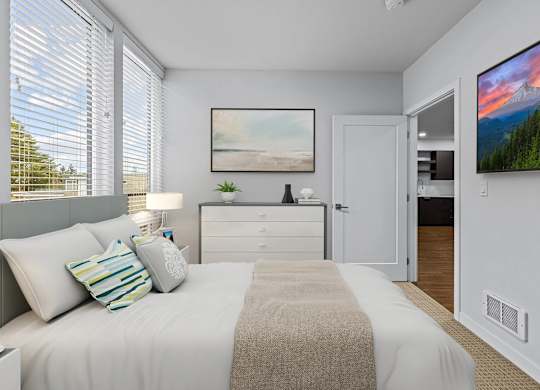A bedroom with a bed, nightstand, and a painting on the wall.