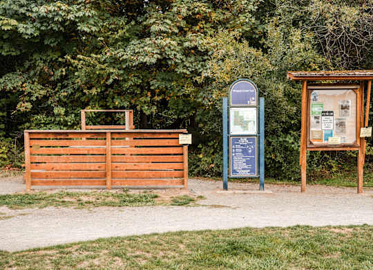 A signboard and a board with information are placed in front of a wooden gate.