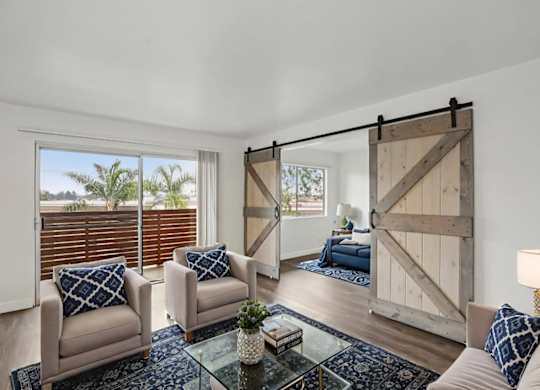 A living room with a glass coffee table and a sliding barn door.