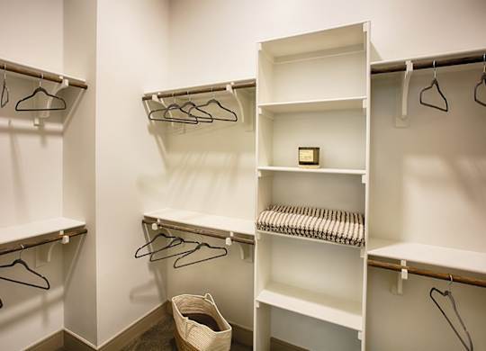 A white closet with clothes hangers and shelves.