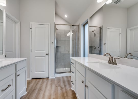 a white bathroom with two sinks and a shower