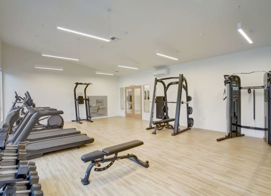 a gym with treadmills and weights in a building with white walls