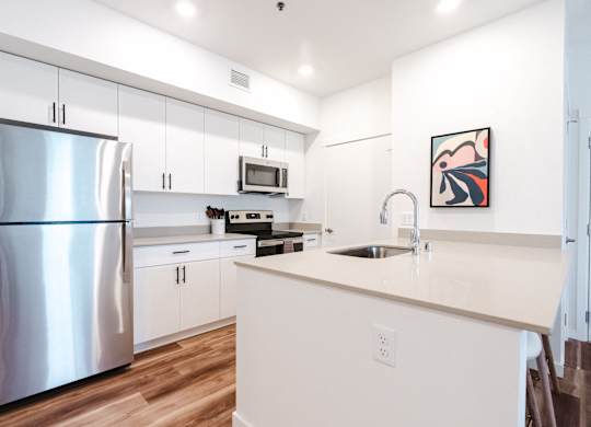 A modern kitchen with a stainless steel refrigerator and white cabinets.