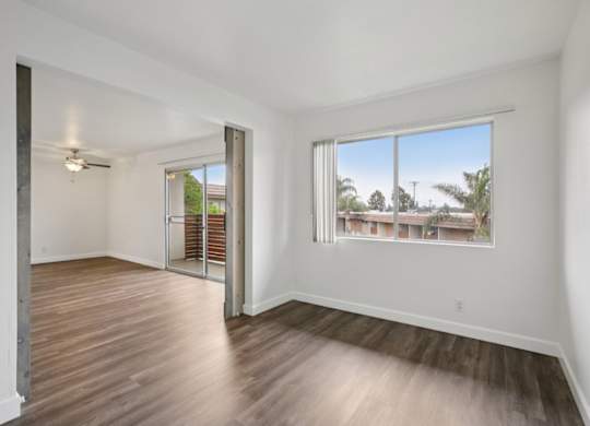 A room with a sliding door and a window overlooking a residential area.