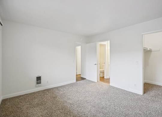 A sparsely furnished room with a carpeted floor and white walls.