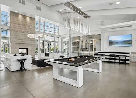 A billiard table is in the middle of a room with a white and black color scheme.