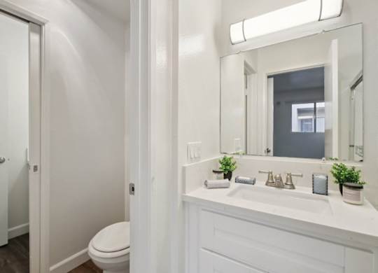 A white bathroom with a toilet, sink, and mirror.