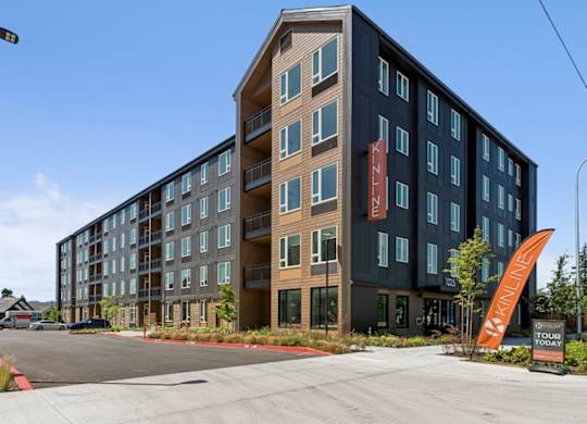 A large multi-story building with a parking lot in front.