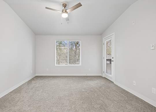 A room with a ceiling fan and carpeted floor.