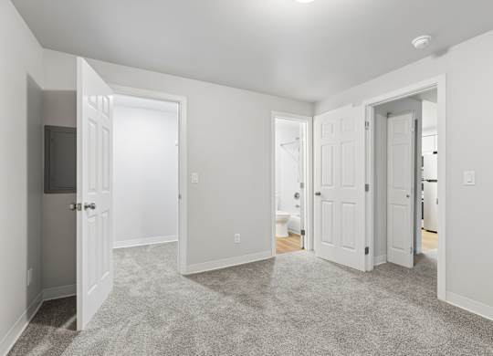 A spacious, empty room with carpeted floor and white walls.