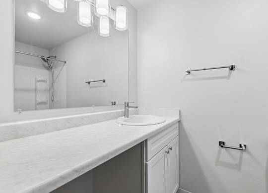 A white bathroom with a sink and mirror.