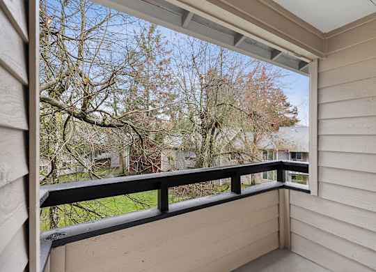 A balcony with a black railing and a view of trees and a building.