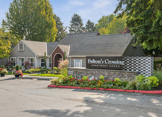 A sign for Fulton's Crossing Apartment Homes is in front of a house.