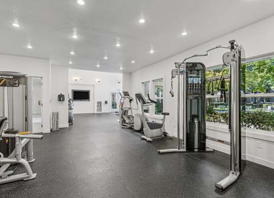 A spacious gym with various exercise equipment and a mirror on the wall.
