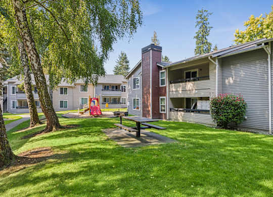 A playground with a slide is in the front yard of a house.