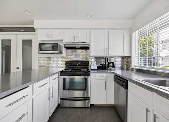 A modern kitchen with white cabinets and stainless steel appliances.