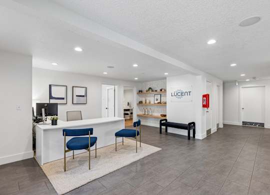 A spacious office with a white reception desk and blue chairs.