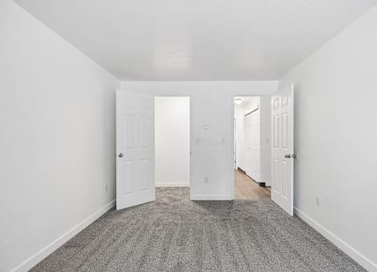 A hallway with a carpeted floor and white walls.