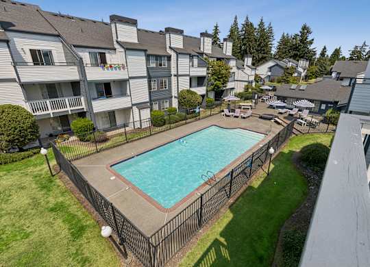 A swimming pool surrounded by a fence and apartment buildings.