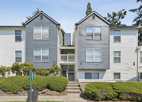 A grey apartment building with a green lawn in front.