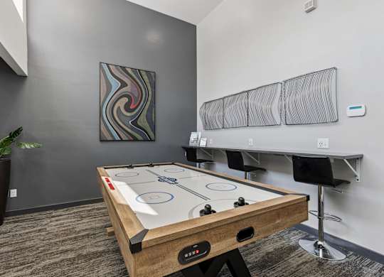 A pool table in a room with a plant and a painting on the wall.
