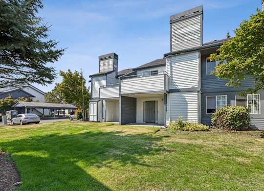 A modern house with a grey exterior and a large front yard.