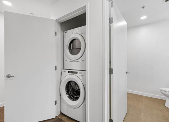 A white door is open to reveal a white washing machine.