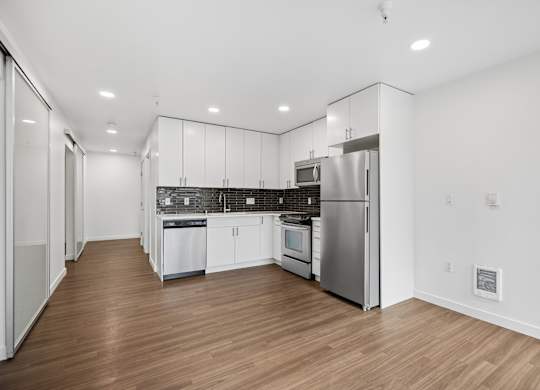 A modern kitchen with stainless steel appliances and wooden floors.