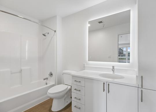 A white bathroom with a toilet, sink, and mirror.