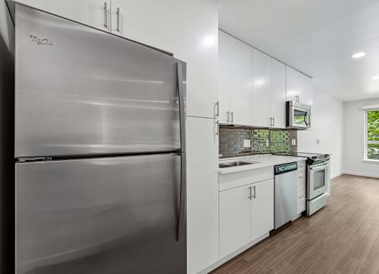 A modern kitchen with a stainless steel refrigerator and white cabinets.