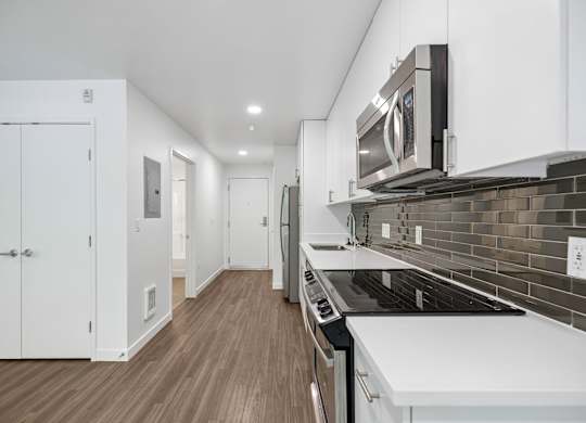 A modern kitchen with white cabinets and a black stove top.