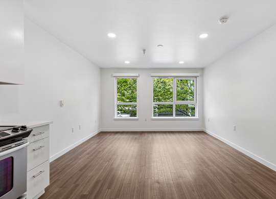 A white room with a wood floor and a window with a view of trees.