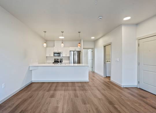 A spacious room with a long white counter and wooden flooring.