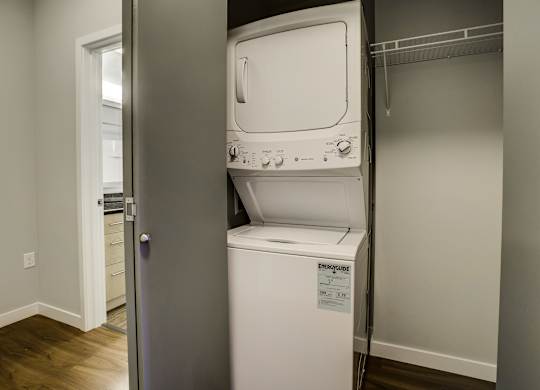 A white dishwasher is in a narrow space between a wall and a door.
