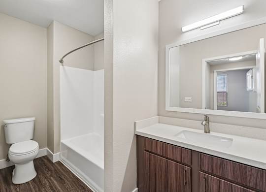 A white toilet sits next to a white bathtub in a bathroom.