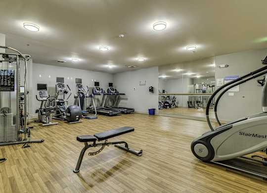 A gym with a variety of equipment including treadmills, weights, and exercise machines.