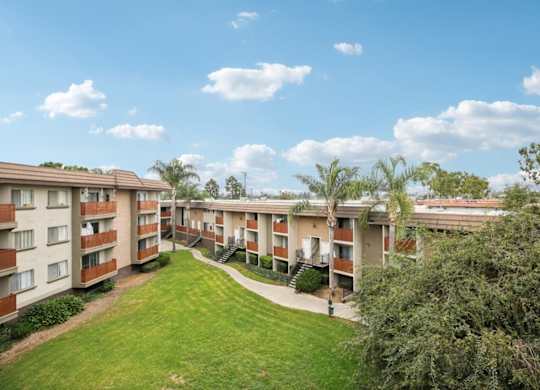 A view of apartment buildings with a green lawn in the foreground.