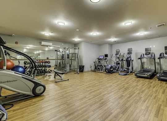 A gym with a variety of equipment including treadmills, stationary bikes, and weight machines.