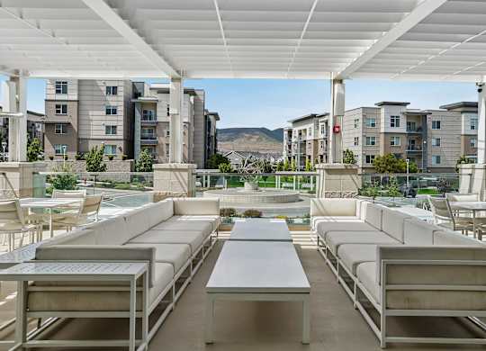 A patio with white furniture and a table is covered by a white roof.