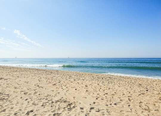 A sandy beach with waves coming in from the ocean.