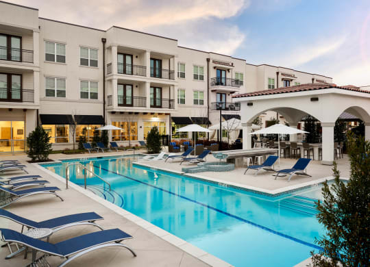 The Dylan  swimming pool with chaise lounge chairs and umbrellas in front of a building