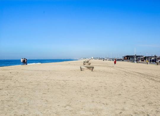 A beach with people and chairs under a clear sky.