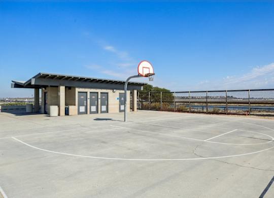 A basketball court with a basketball hoop and a small building.
