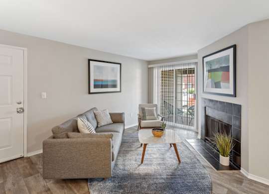 A living room with a grey couch and a fireplace.