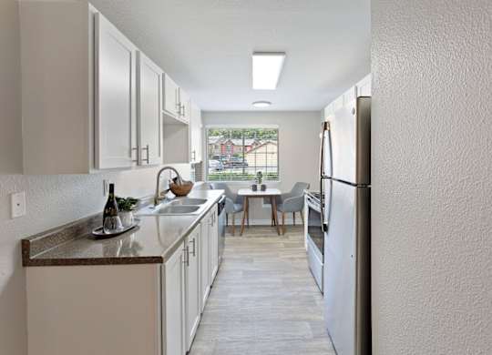 A kitchen with white cabinets and a wooden floor.