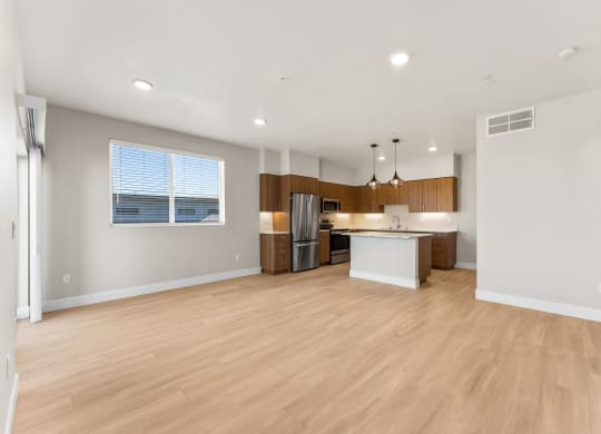 an open kitchen and living room with wood flooring and a large window