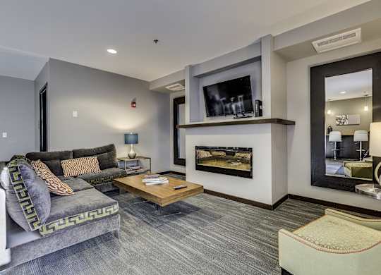 A modern living room with a grey couch and a fireplace.