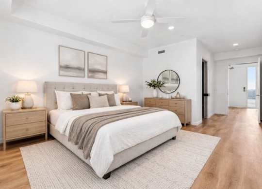 A bedroom with a large bed, a dresser, and a mirror.