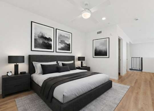 A bedroom with a large bed, two nightstands, and pictures on the wall.