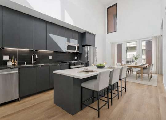 A modern kitchen with dark grey cabinets and a white island.